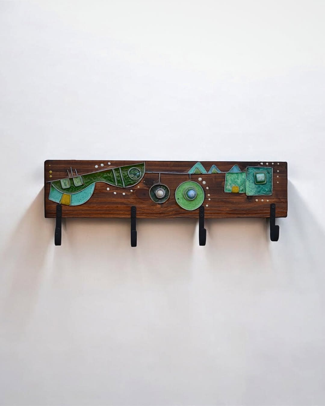 Percheros artesanales de madera con ganchos metálicos, exhibidos en pared